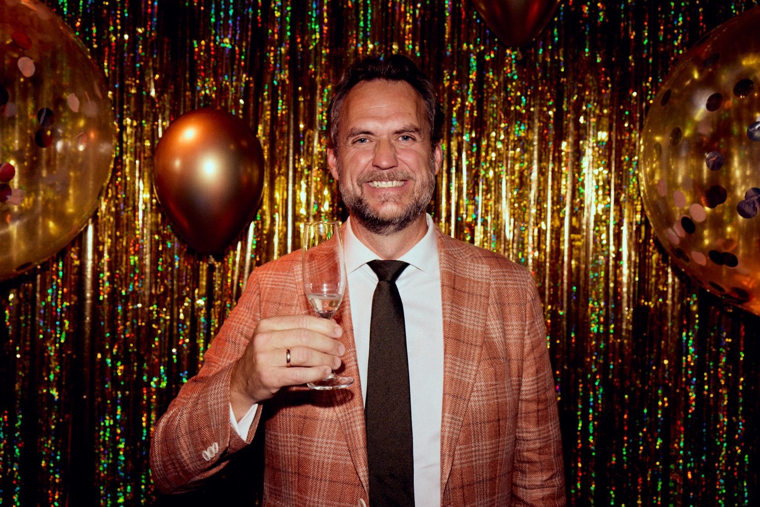 A smiling portrait in a checked jacket against golden streamers